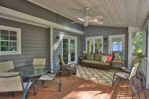 Covered back porch with open views of backyard and nature by Deck Creations.