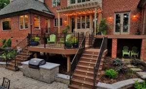 Stunning brick house with custom deck and black metal railing by Deck Creations.