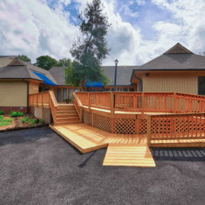 A sprawling wooden porch, skillfully designed and built by Deck Creations, boasts a handicap-accessible ramp for convenience.