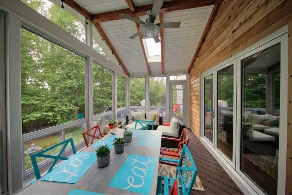 Outdoor covered patio space with raised ceilings and wood siding by Deck Creations.