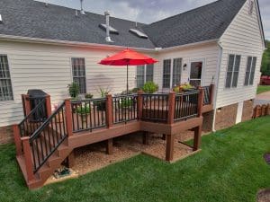 Small back deck with brown wood and black railing designed by Deck Creations.
