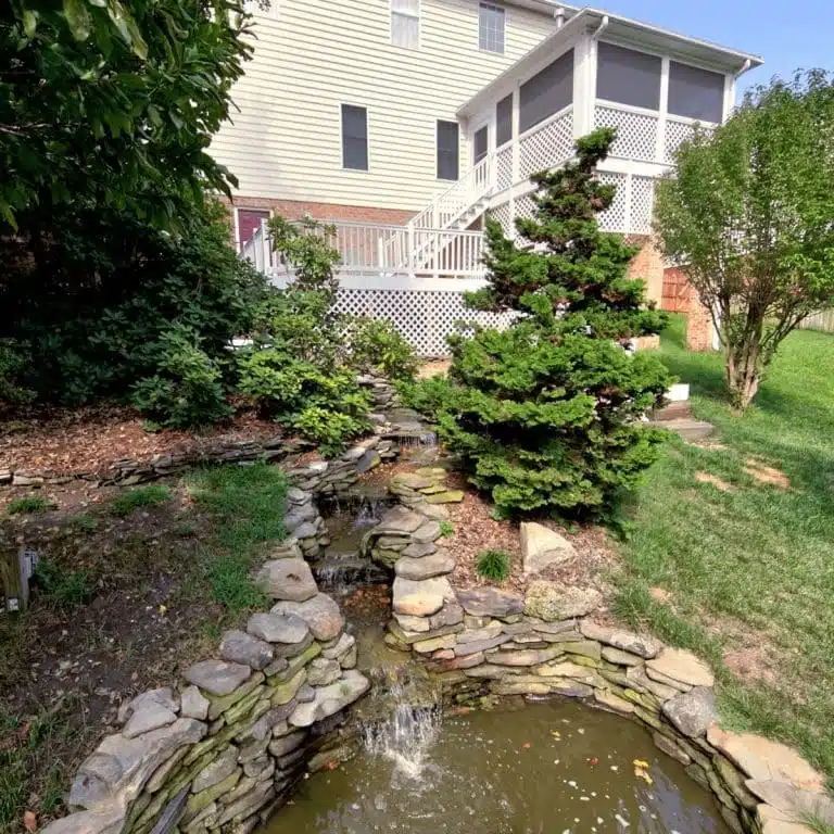 Custom Wooden Deck Leading to a Garden and Pond by Deck Creations.