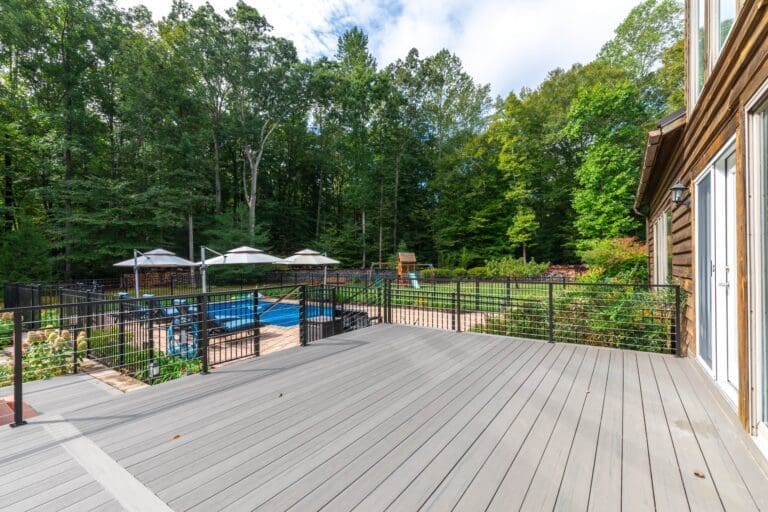 Large outdoor patio deck that leads out to a pool, garden, and open backyard area.