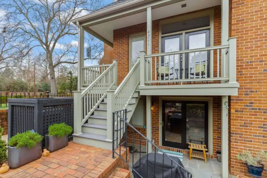 A quaint covered porch and staircase, skillfully crafted by Deck Creations, providing access to a charming brick condo or apartment.