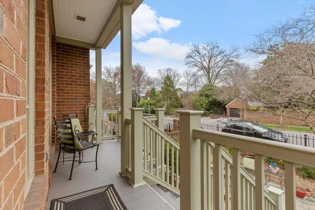 A quaint covered porch and staircase, skillfully crafted by Deck Creations, providing access to a charming brick condo or apartment.