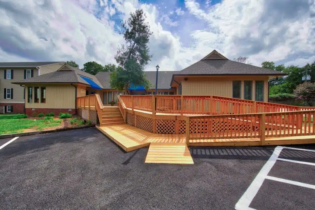 A sprawling wooden porch, skillfully designed and built by Deck Creations, boasts a handicap-accessible ramp for convenience.