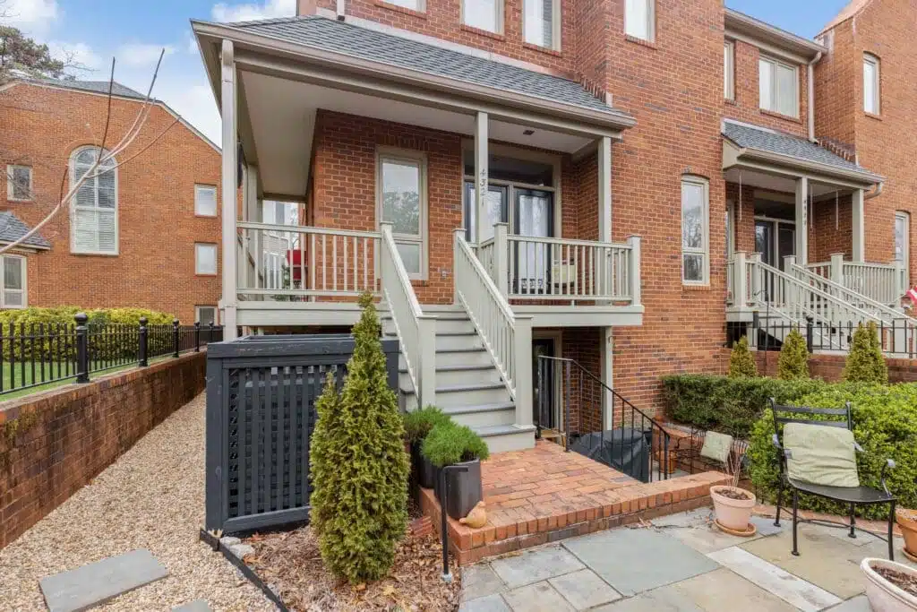 A quaint covered porch and staircase, skillfully crafted by Deck Creations, providing access to a charming brick condo or apartment.