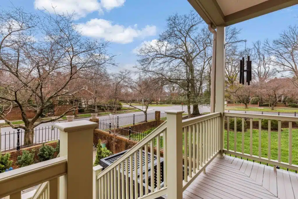 A quaint covered porch and staircase, skillfully crafted by Deck Creations, providing access to a charming brick condo or apartment.