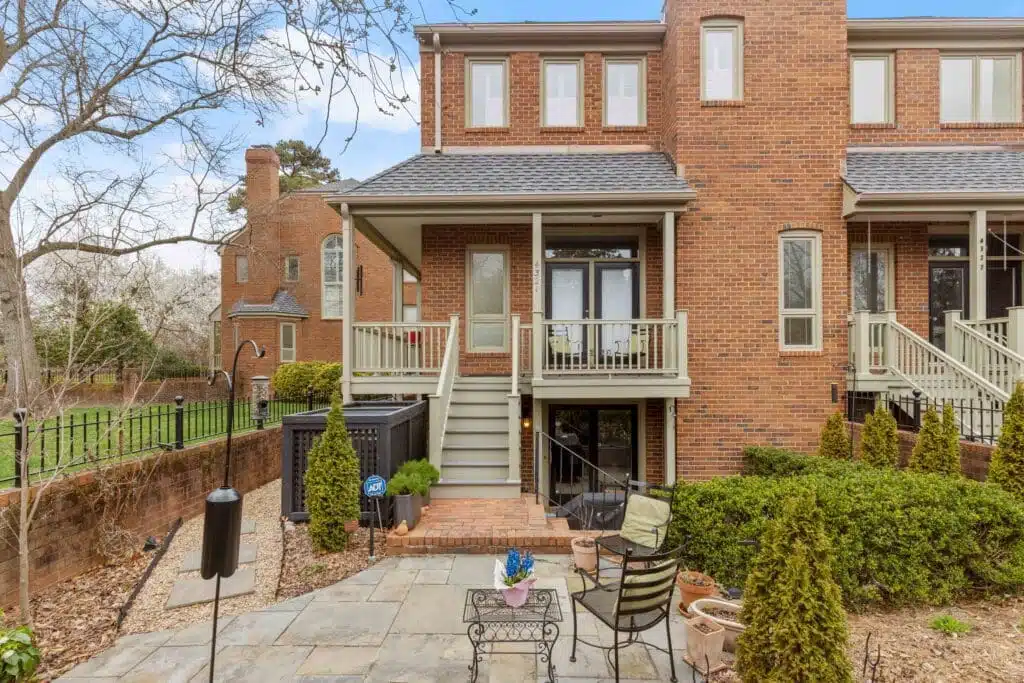 A quaint covered porch and staircase, skillfully crafted by Deck Creations, providing access to a charming brick condo or apartment.