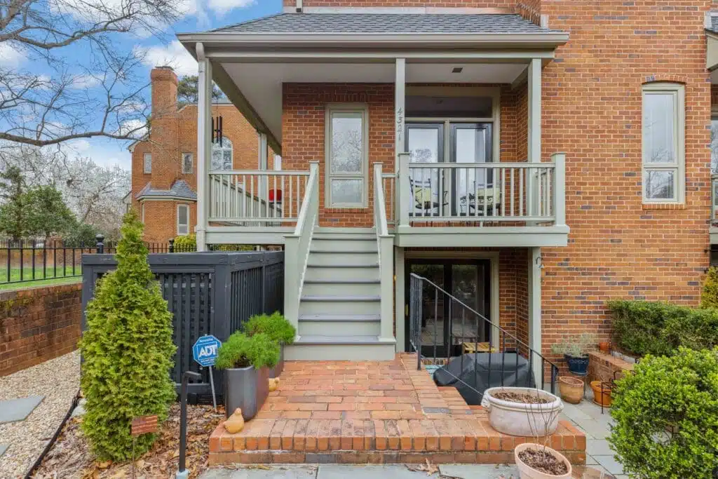 A quaint covered porch and staircase, skillfully crafted by Deck Creations, providing access to a charming brick condo or apartment.