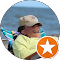 Lounging on a beach chair by the sea, wearing a beige cap and sunglasses, this person embodies seaside serenity. The image’s bottom right corner features an orange star badge, adding a touch of distinction to the peaceful scene.