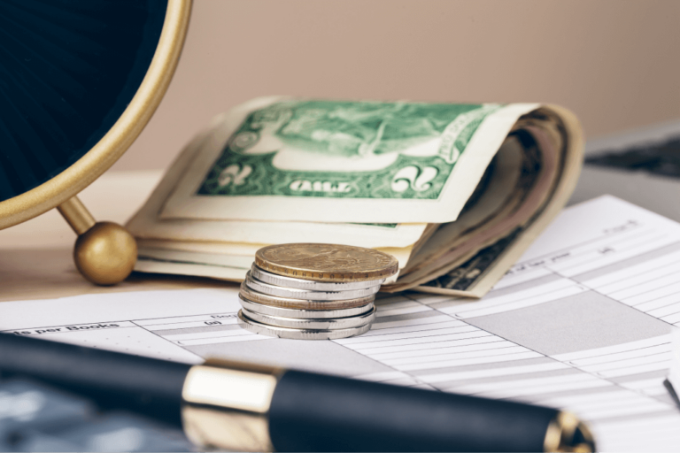 A stack of coins and folded dollar bills rests on top of financial documents, akin to securing the siding of a house with strategic precision, with a pen nearby.