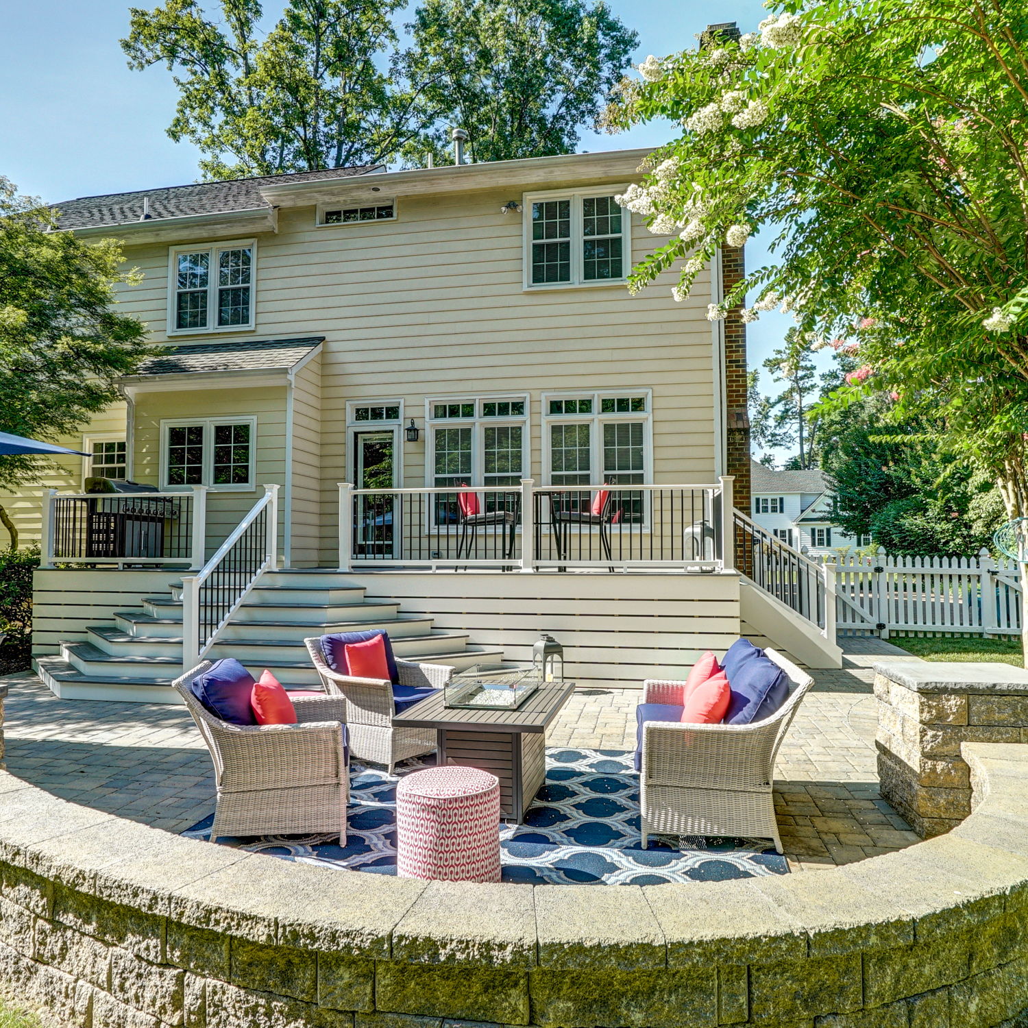 Custom-built deck with stairs leading from the back of the house to a charming small stone hardscape patio.