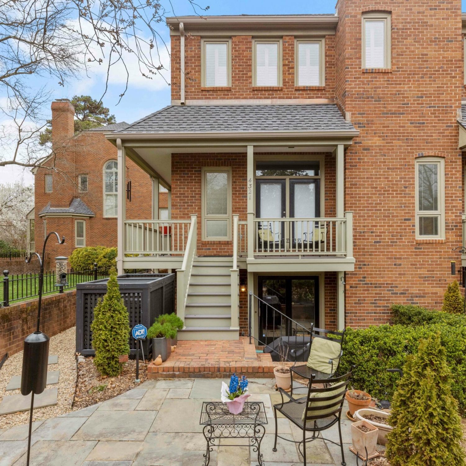 A quaint covered porch and staircase, skillfully crafted by Deck Creations, providing access to a charming brick condo or apartment.